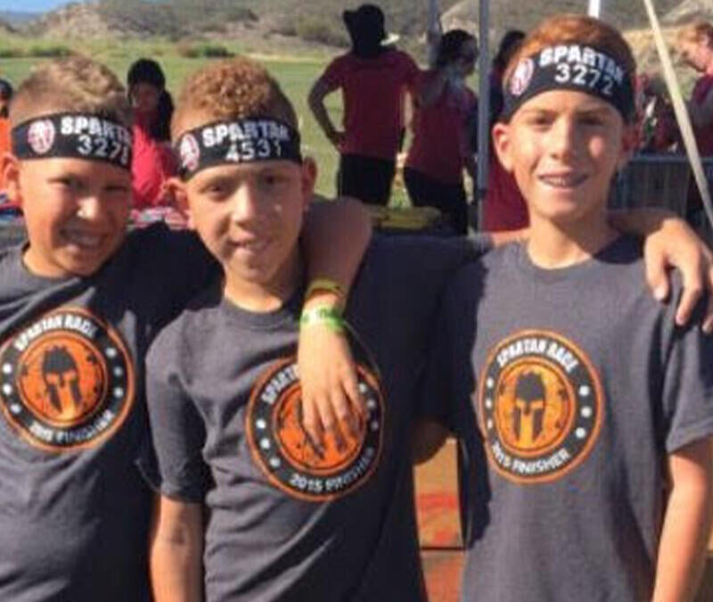 Three boys posing for a photo at an obstacle course.