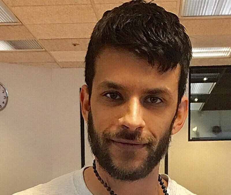 A man with a beard is smiling in an office.