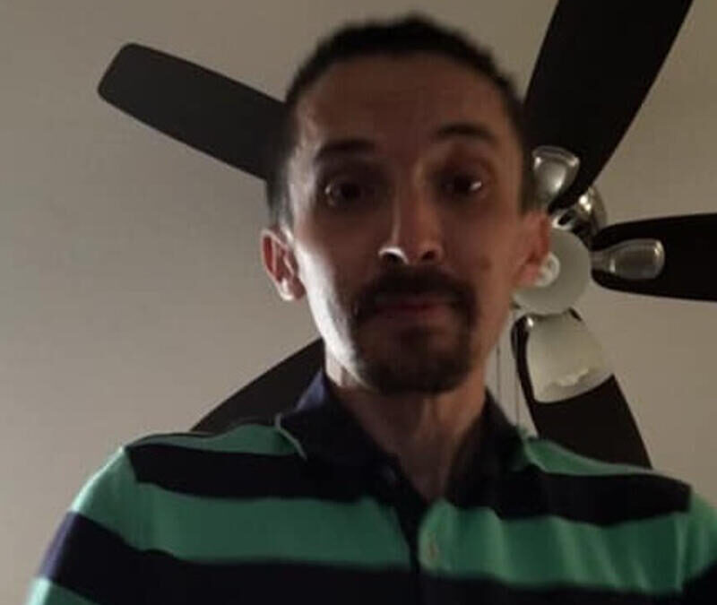 A man is standing in front of a fan.
