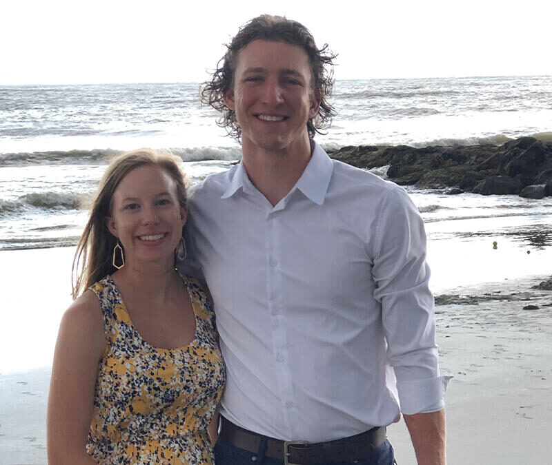 A man and woman posing for a photo on the beach.