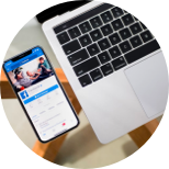 A laptop with a phone on it next to a wooden table.