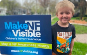 A young boy holding a sign that says make nf visible.