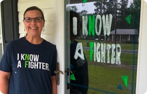A woman standing in front of a door with a sign that says i know a fighter.