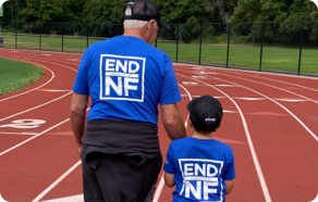 A man and a boy walking down a track wearing t - shirts that say end nff.