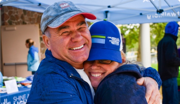 A man and woman hugging under a tent.