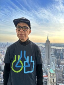 A man in a t - shirt standing in front of the empire state building.