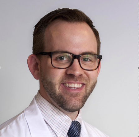 A male doctor wearing glasses and a tie.