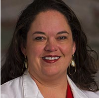 A woman in a white lab coat smiling.