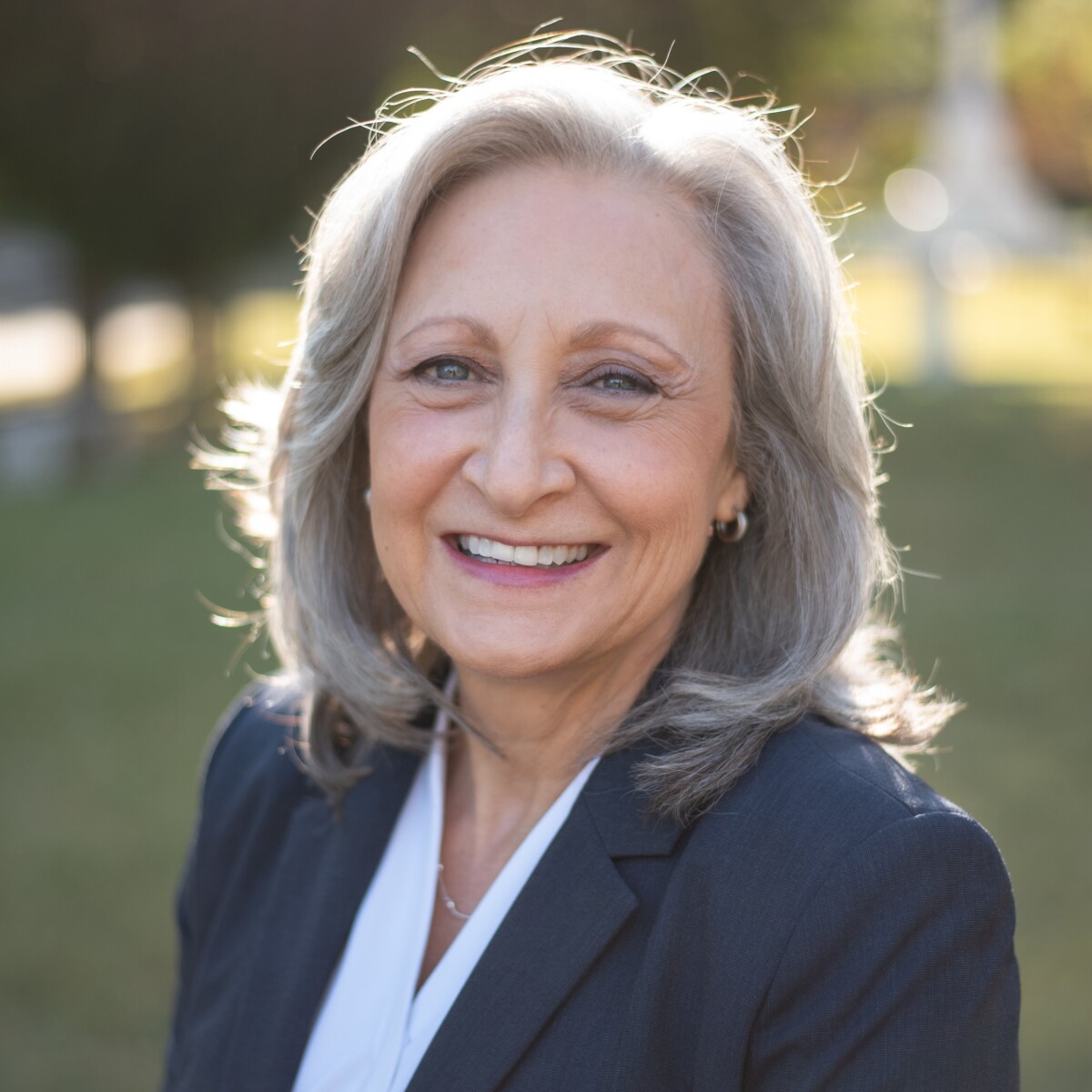 An older woman smiling in a business suit.