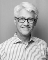 A black and white photo of a man wearing glasses.