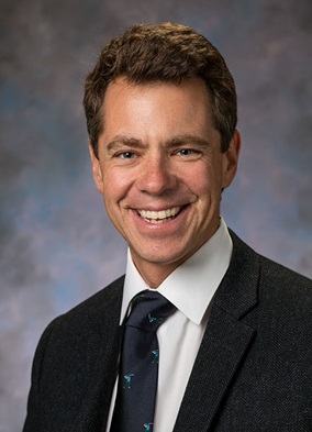 A smiling man in a suit and tie.