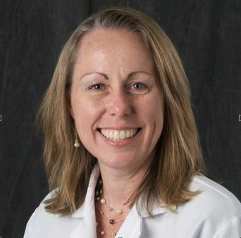 A smiling woman in a white lab coat.