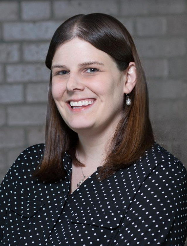 A smiling woman in a black and white polka dot shirt.