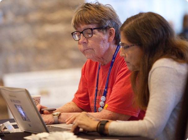 Two women sitting at a table looking at a laptop.