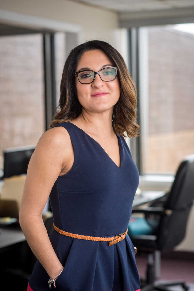 A woman in glasses standing in an office.