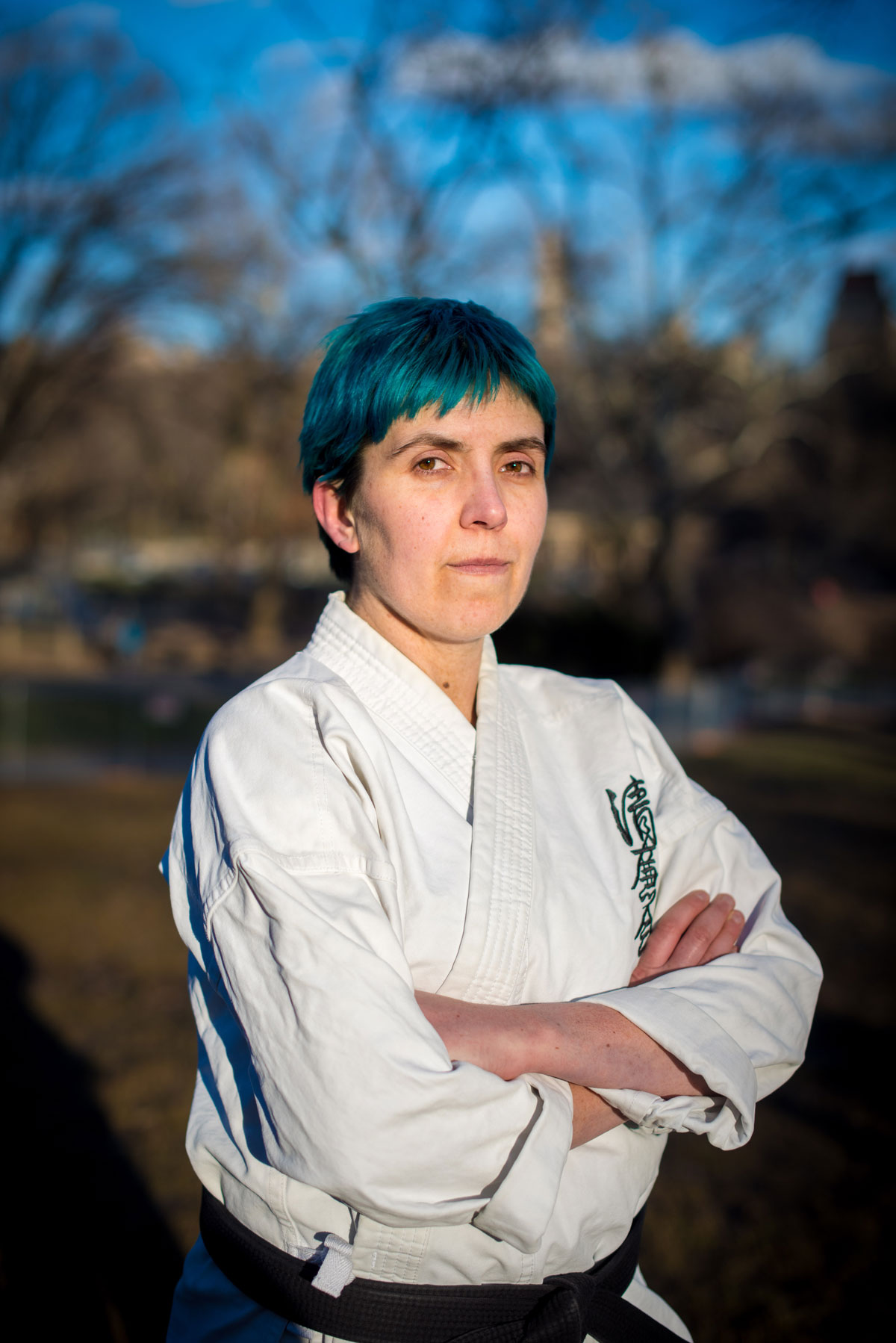 A woman in a karate uniform standing in a park.