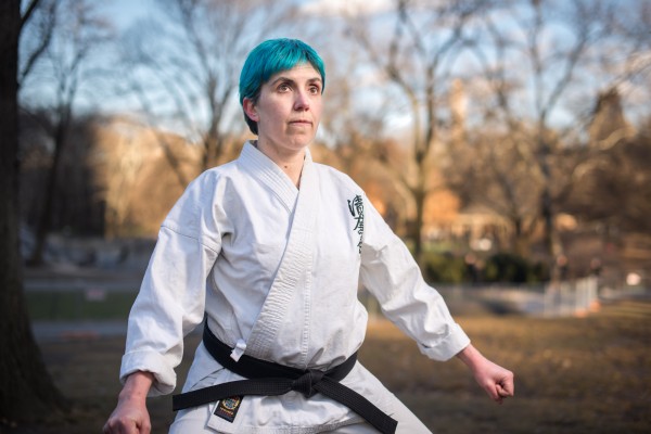 A woman in a karate uniform in a park.