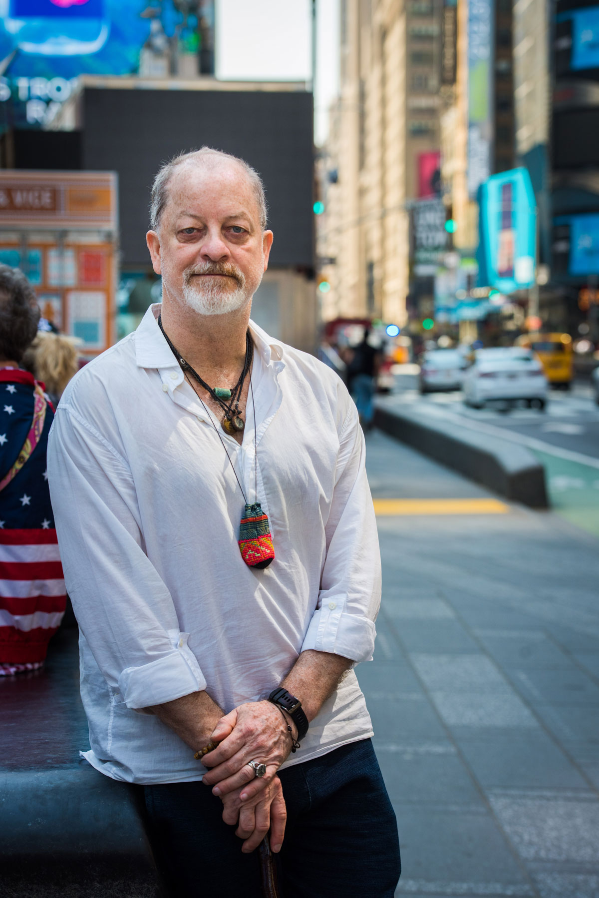 A man in a white shirt leaning against a wall in times square.