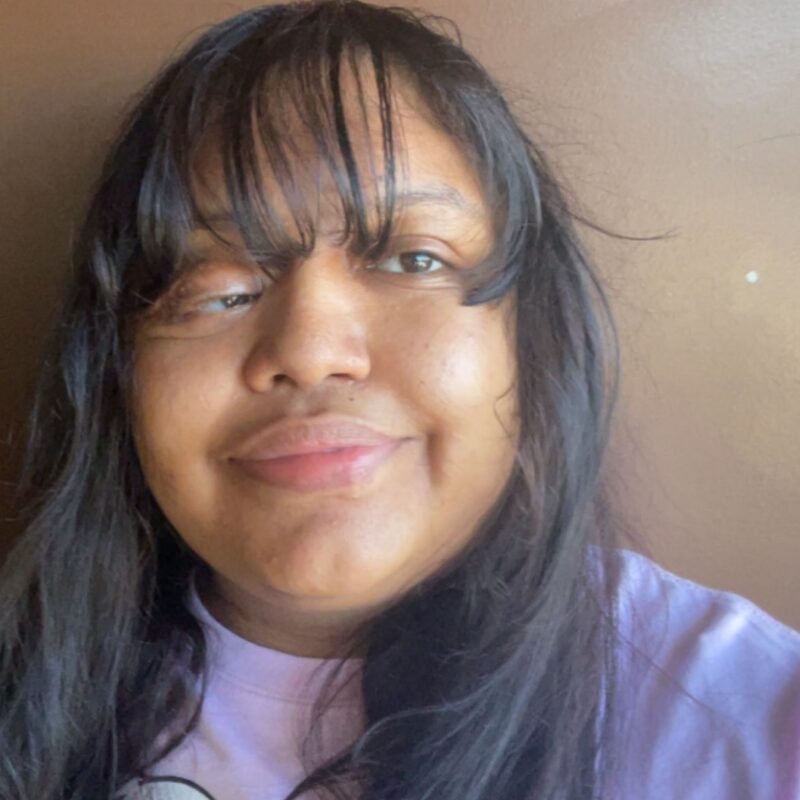 A woman wearing a pink shirt with long hair.