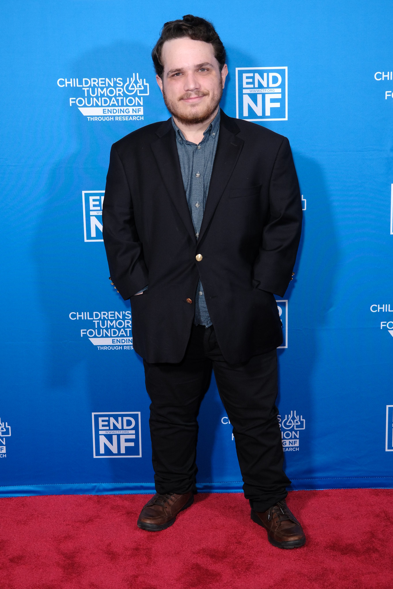 A man in a suit standing on a red carpet.