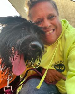 A woman in a yellow hoodie with a black dog.