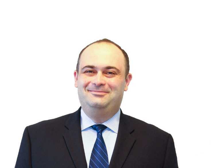 A man in a suit and tie smiling for the camera.