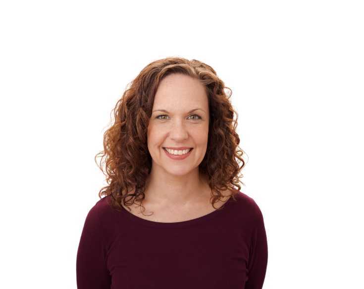 A woman with curly hair smiling for the camera.