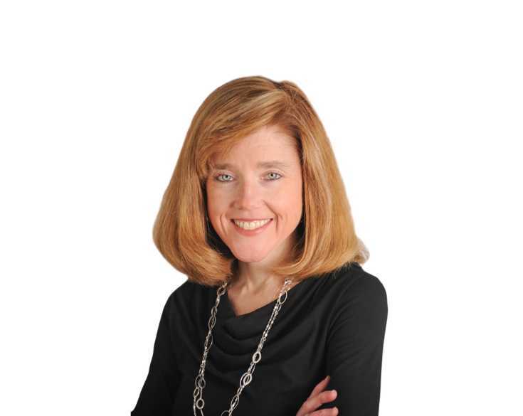 A woman smiling with her arms crossed on a white background.