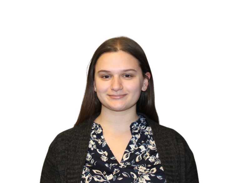 A young woman in a floral shirt standing in front of a white background.