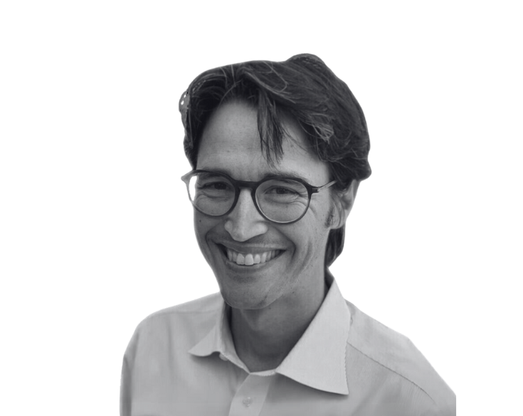 A black and white photo of a smiling man wearing glasses.