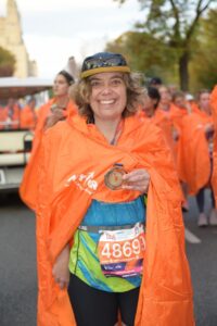 A woman wearing an orange cape in a race.