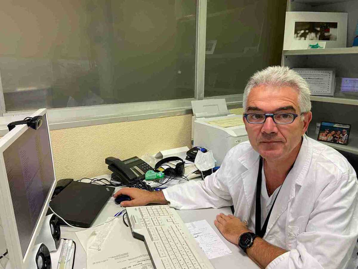 A man in a lab coat sitting in front of a computer.