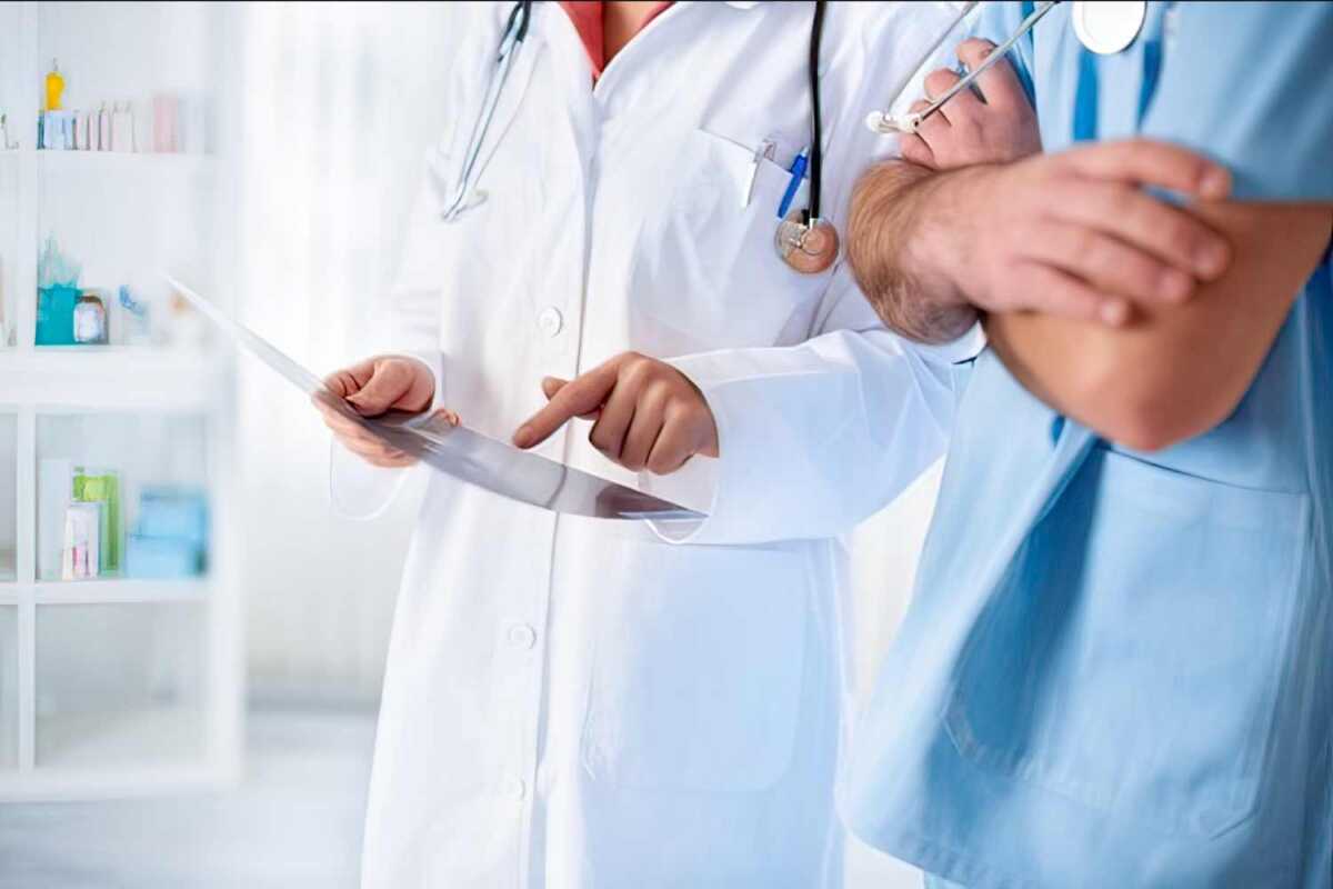 Two doctors standing next to each other holding a clipboard.