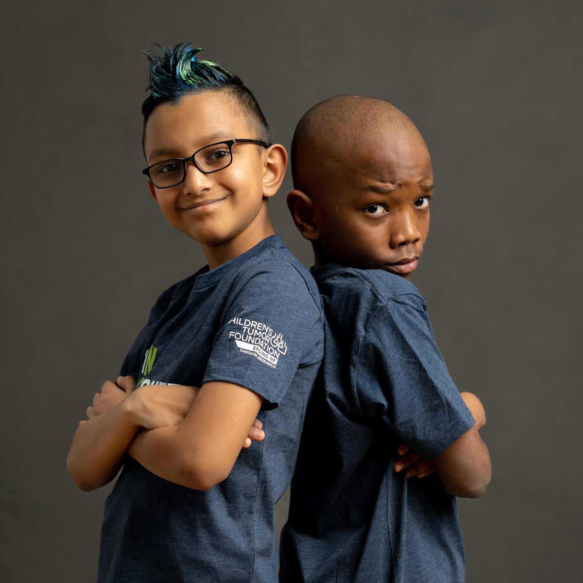 Two boys in blue t - shirts posing for a photo.