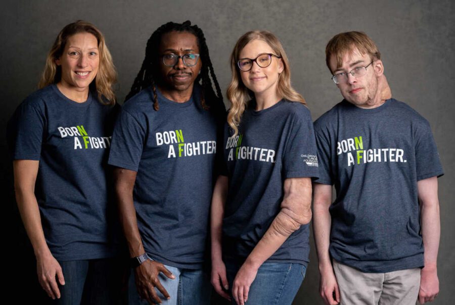 Four adults wearing a shirt that says Born a Fighter