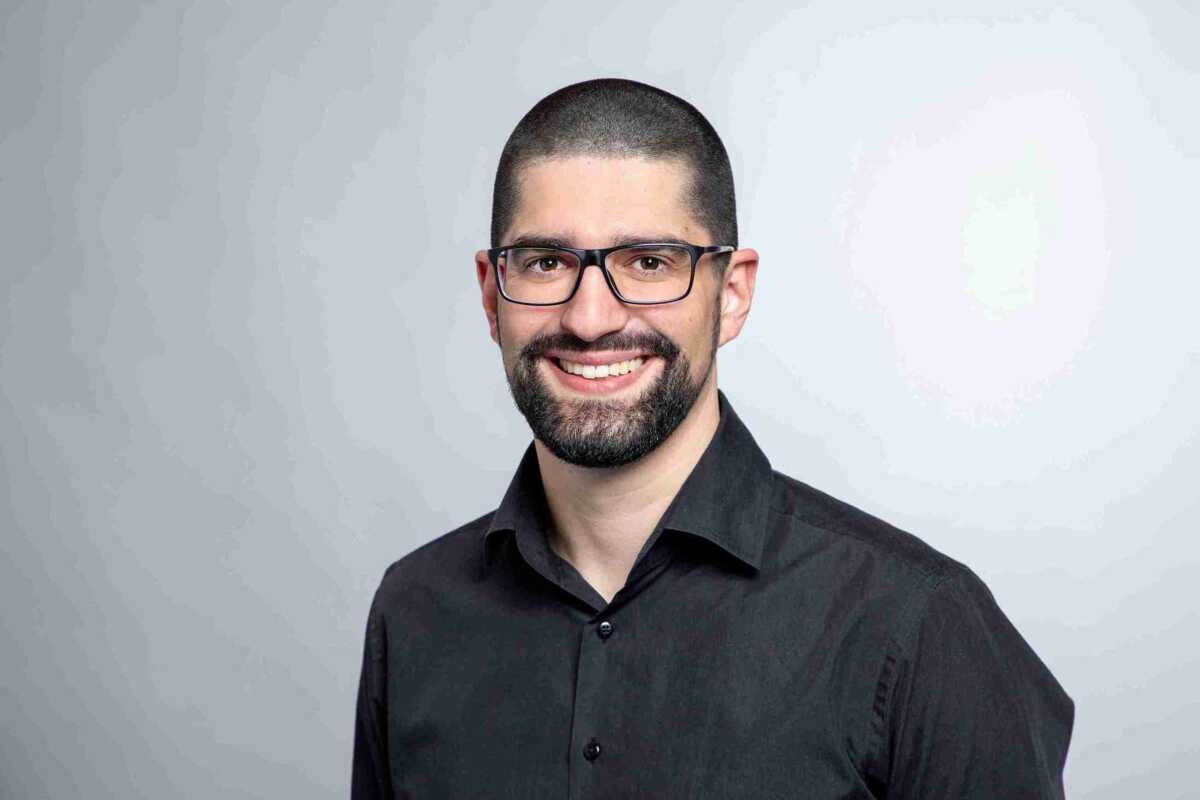 A man with glasses and a beard smiling for the camera.