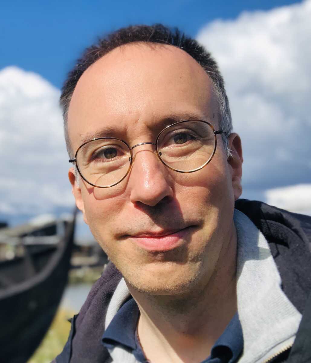 A man with glasses in front of a boat.