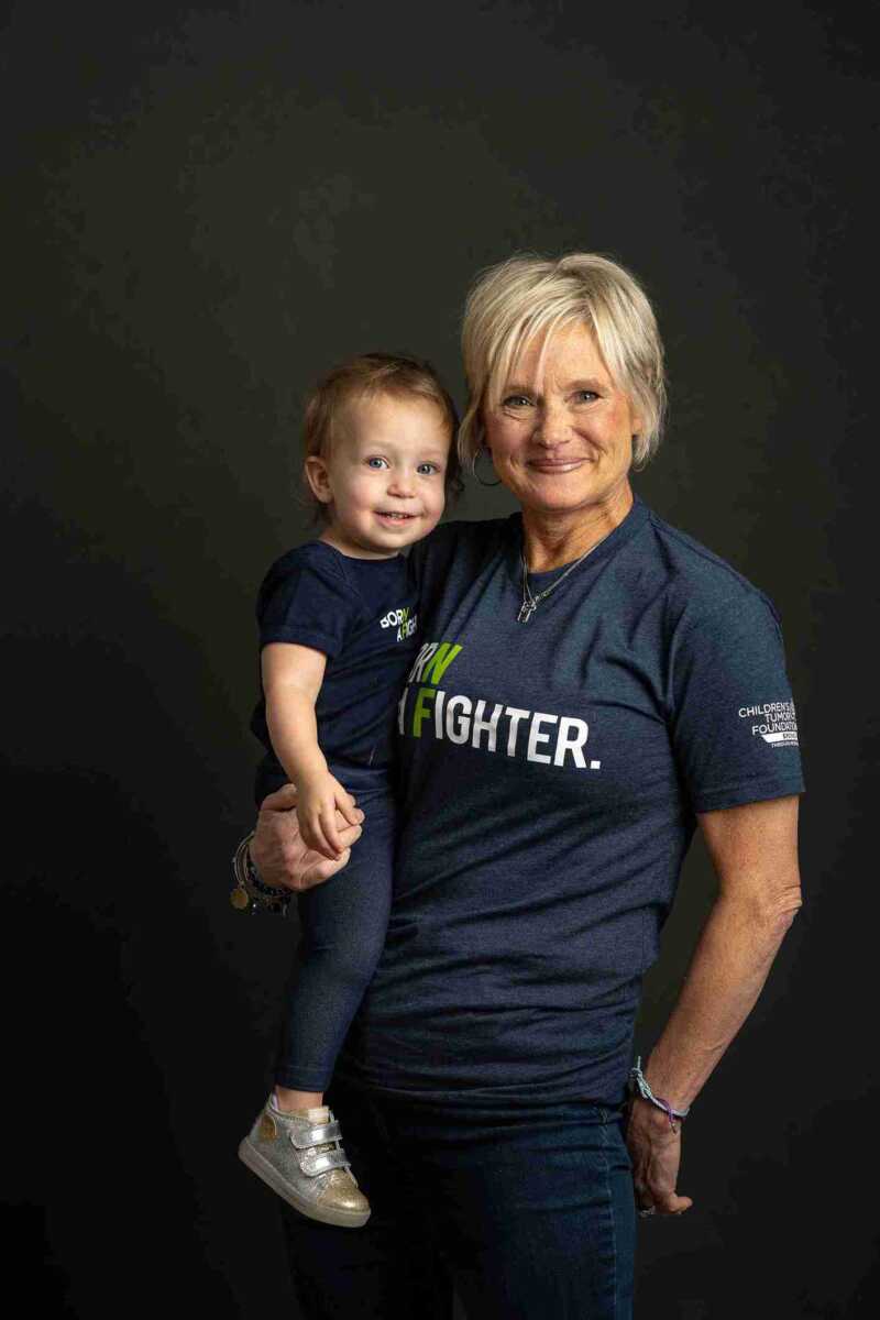 A woman holding a child in a t - shirt that says fighter.