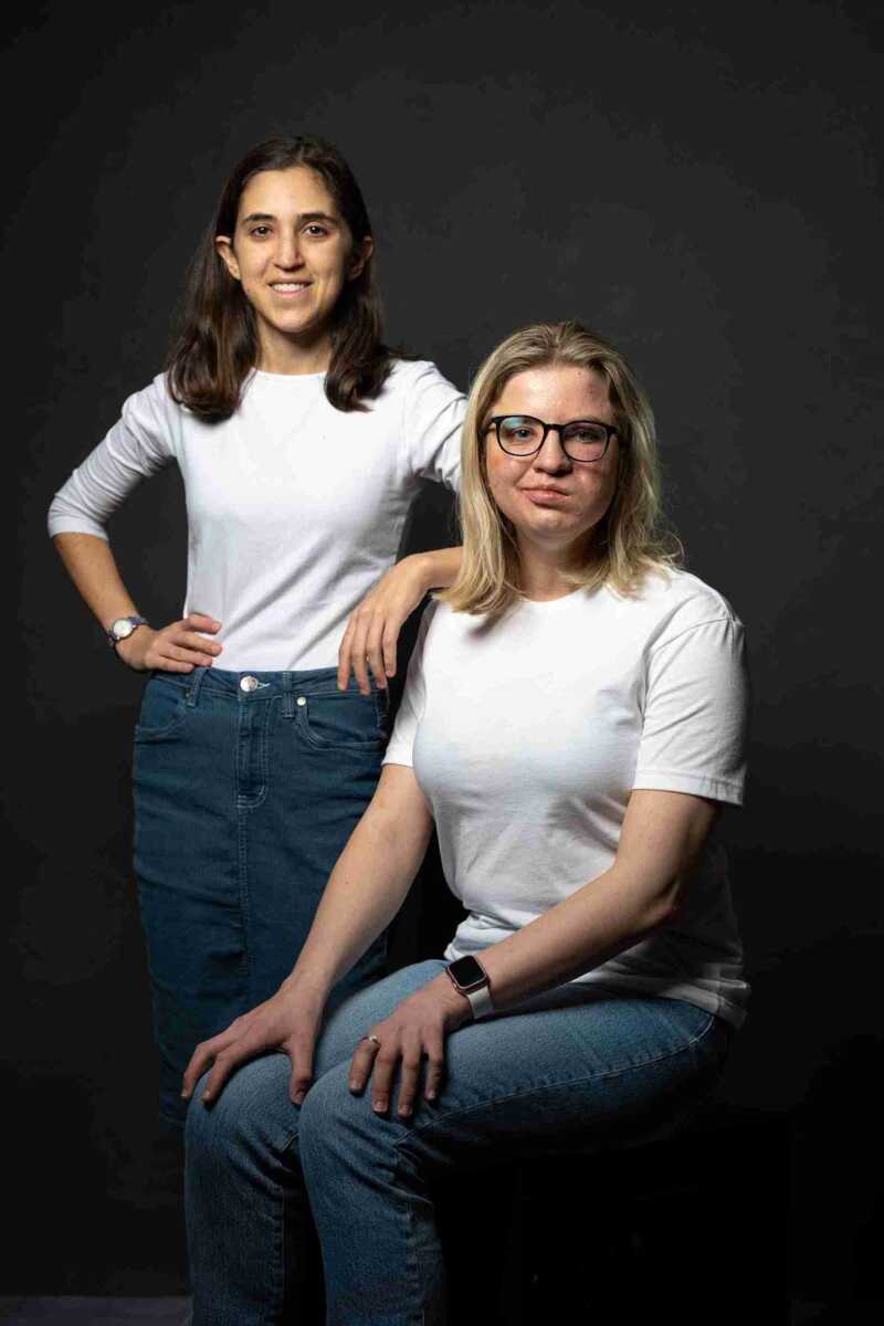 Two women in white t - shirts posing for a photo.