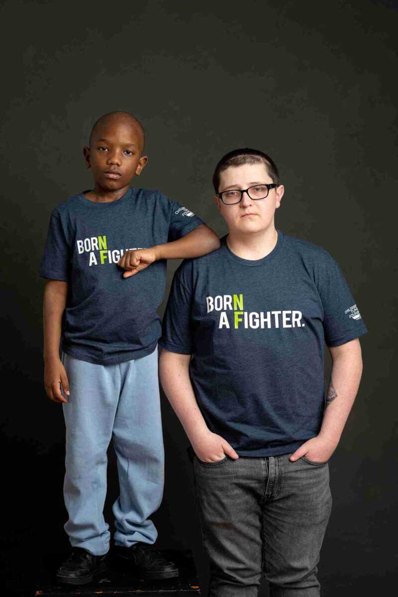 Two boys wearing t - shirts that say 'be a fighter'.