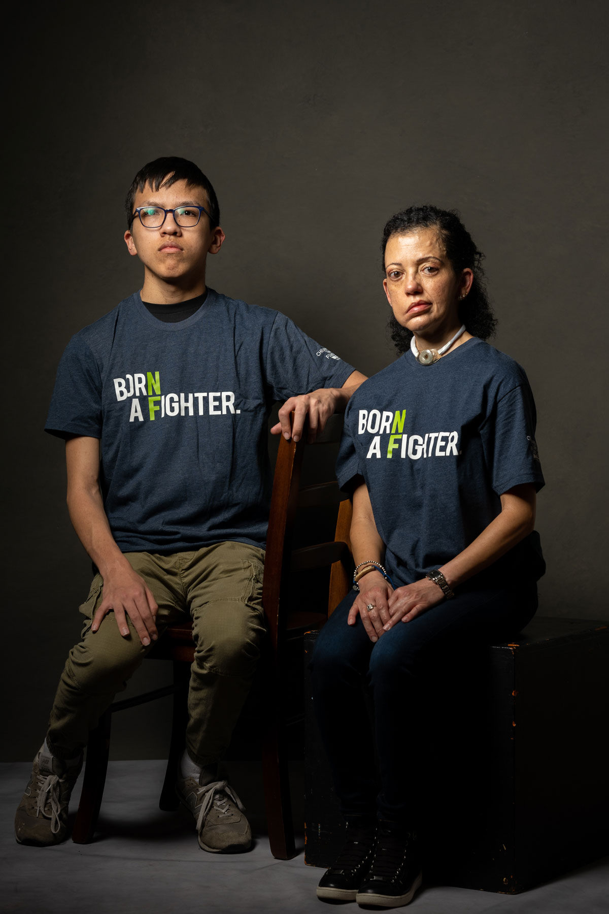 man and woman sitting wearing Born a Fighter shirts