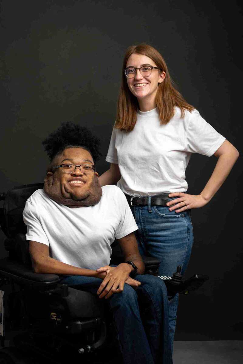 Two people posing for a photo in a wheelchair.
