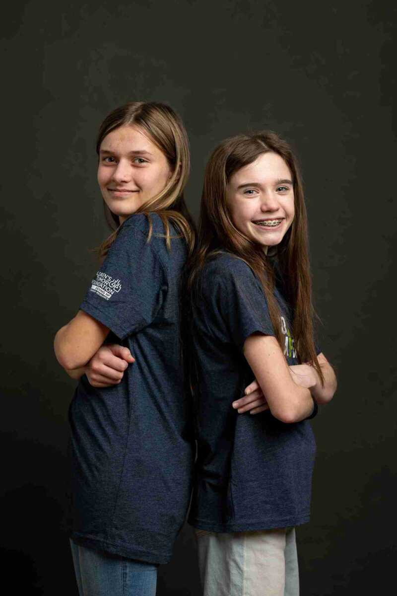 Two girls in blue t - shirts posing for a photo.