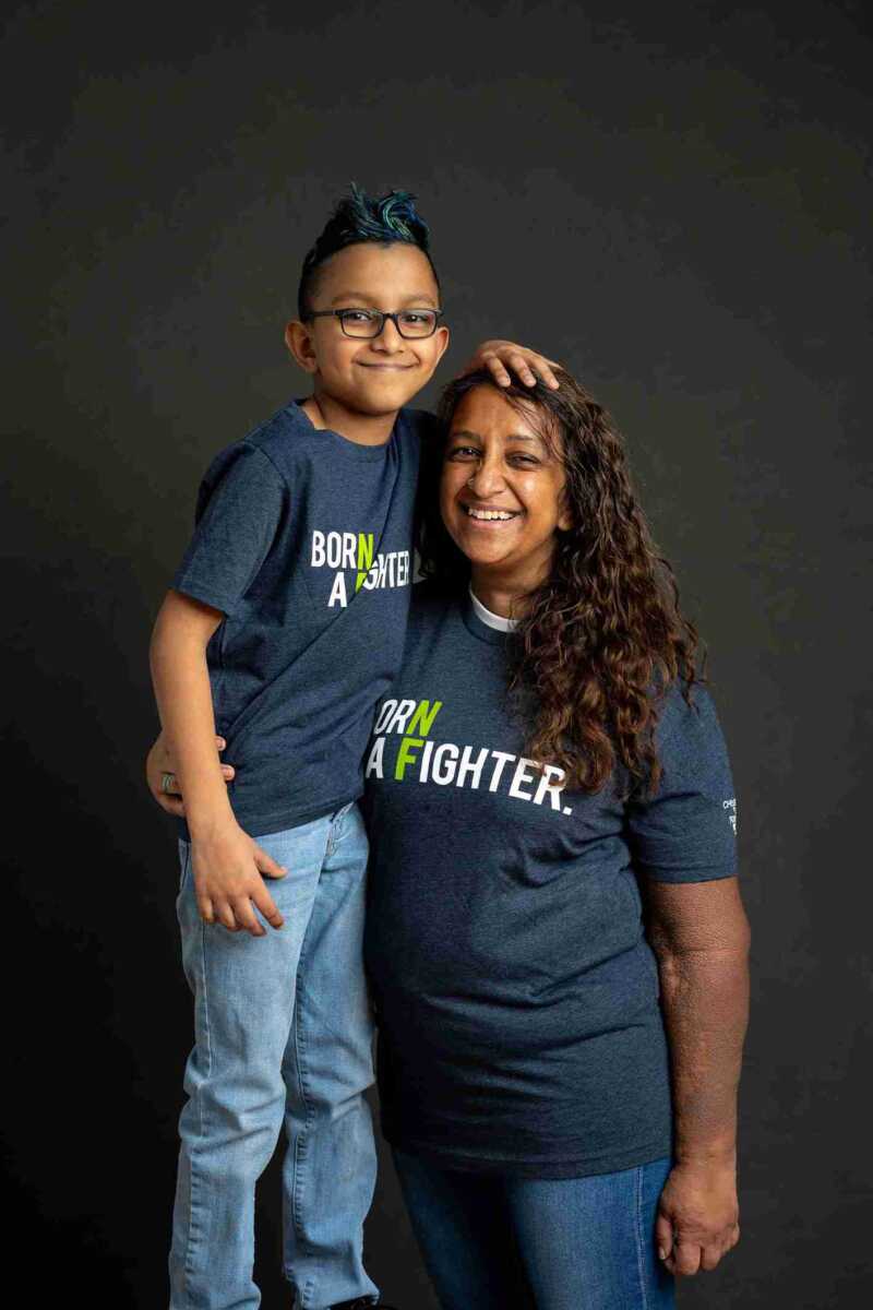 A mother and son posing for a photo in a blue t - shirt.