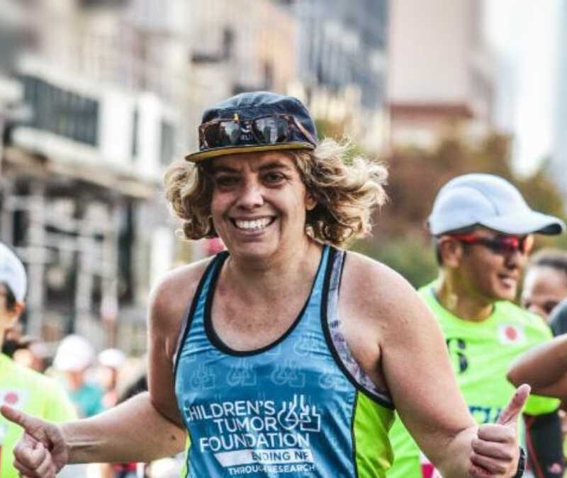 A woman is running a marathon in a city.