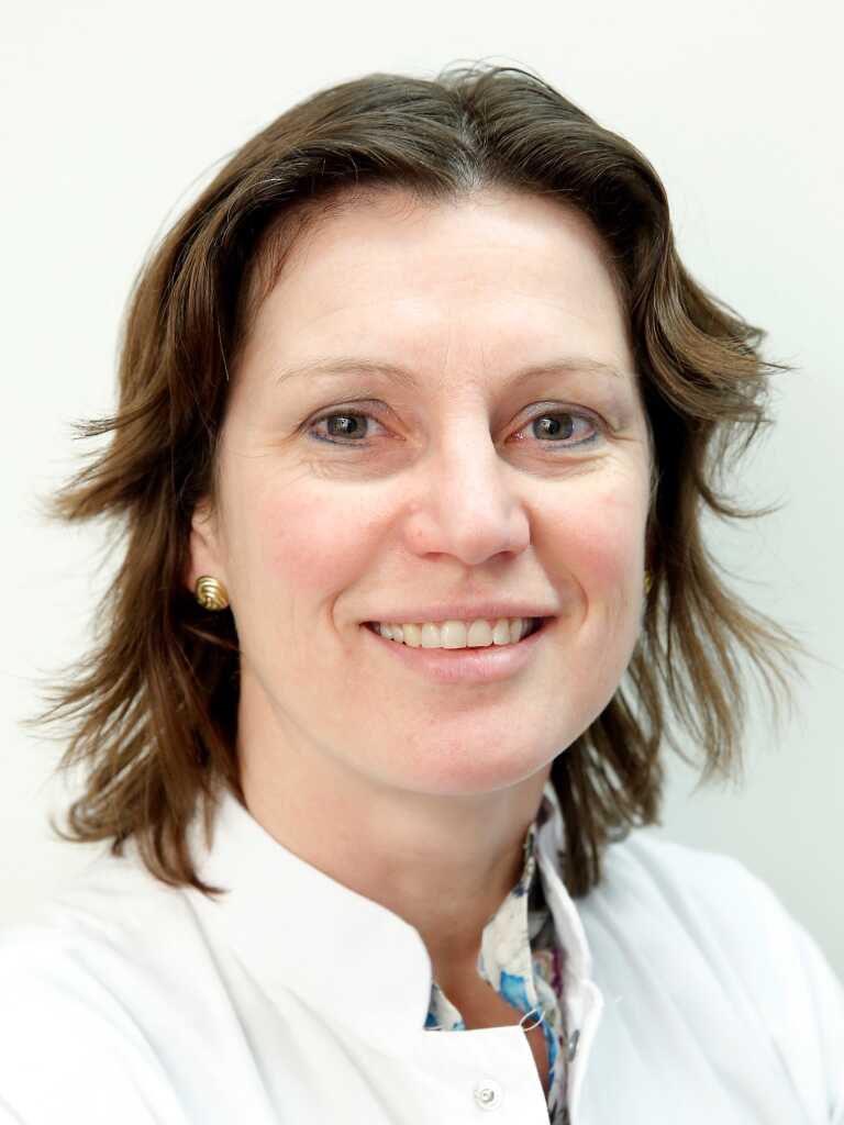 A woman in a white lab coat smiling for the camera.