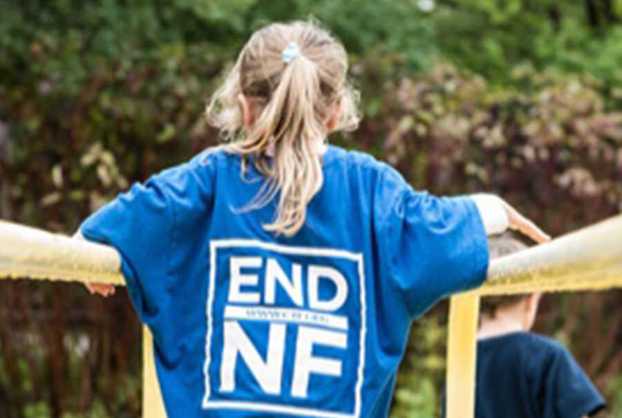 A young girl wearing a blue t - shirt with the words end nf on it.