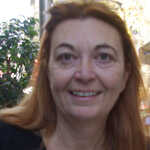 A woman with red hair smiling in a restaurant.