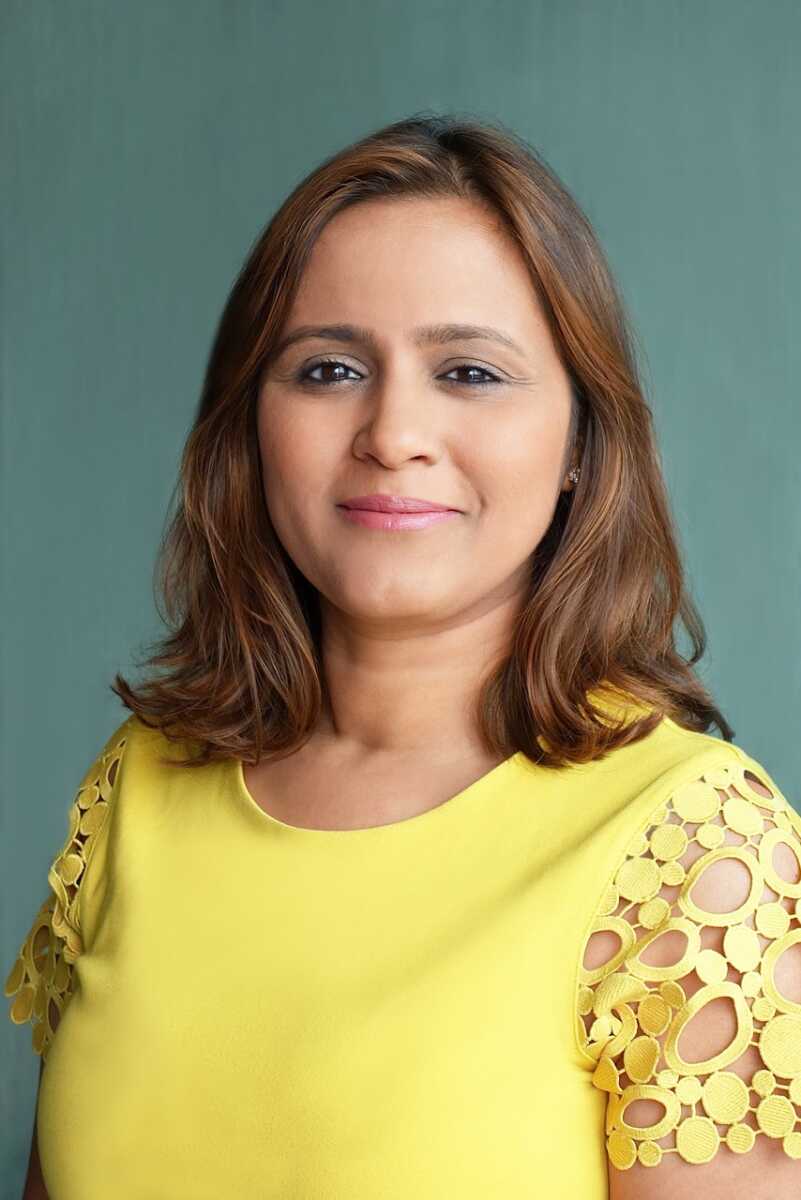 A woman in a yellow shirt posing for a photo.