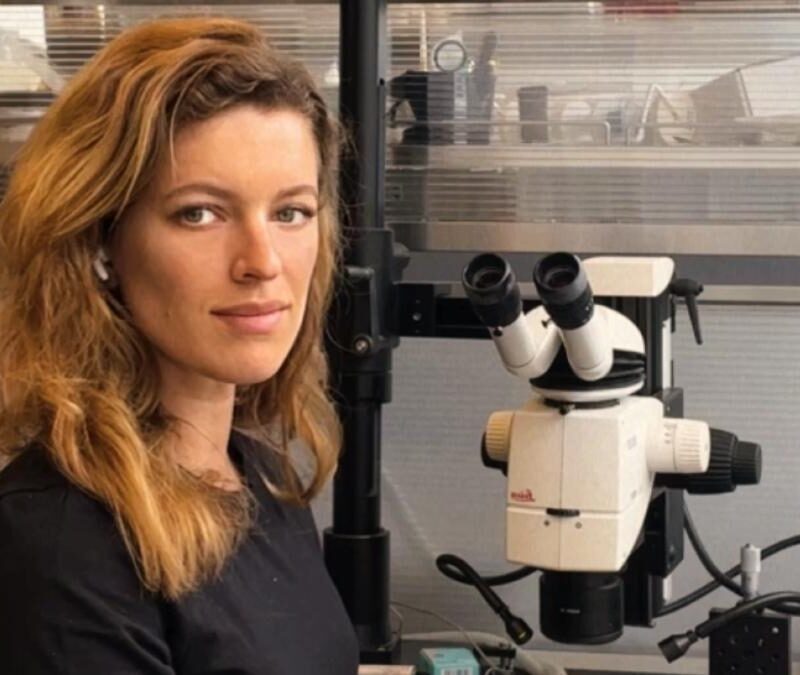 A woman sitting in front of a microscope.